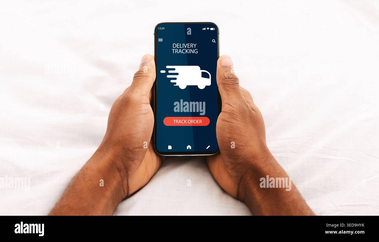 Black man using smartphone with delivery tracking app Stock Photo