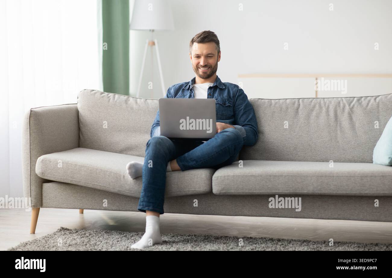 Handsome bearded man using laptop and smiling Stock Photo