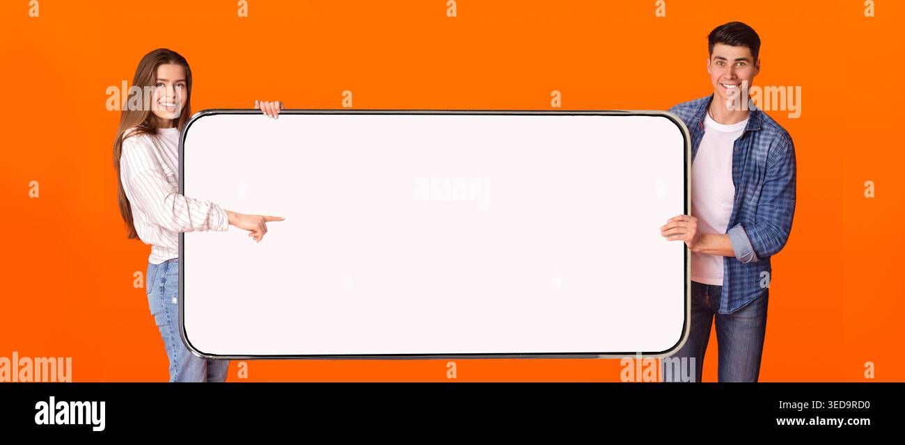 Excited couple pointing at white empty smartphone screen Stock Photo