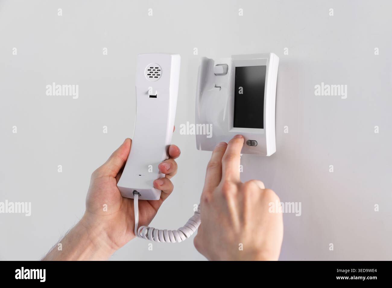 Man with handset pressing button on intercom panel indoors, closeup Stock Photo