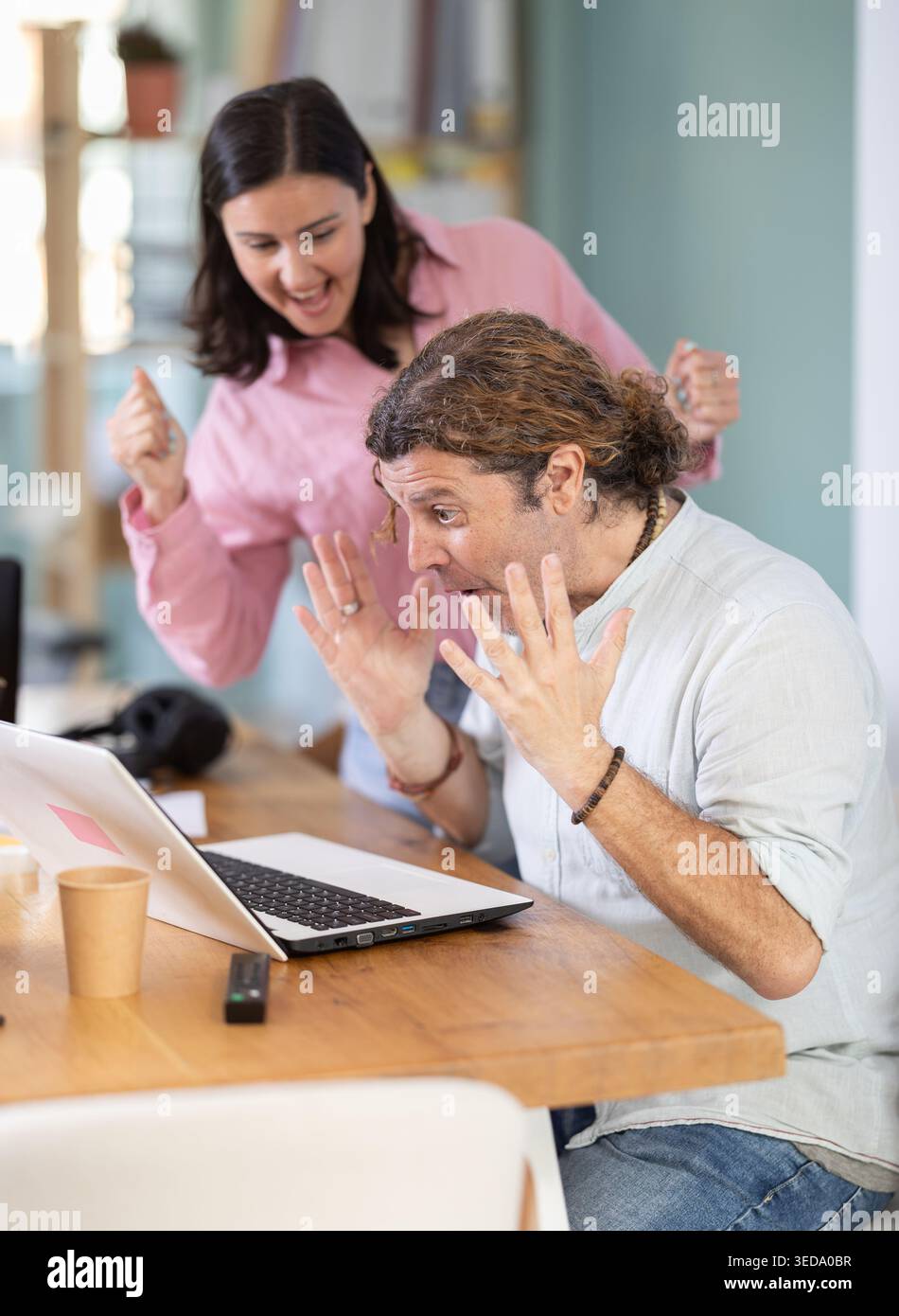 Happy colleagues sharing success while looking at laptop screen Stock Photo
