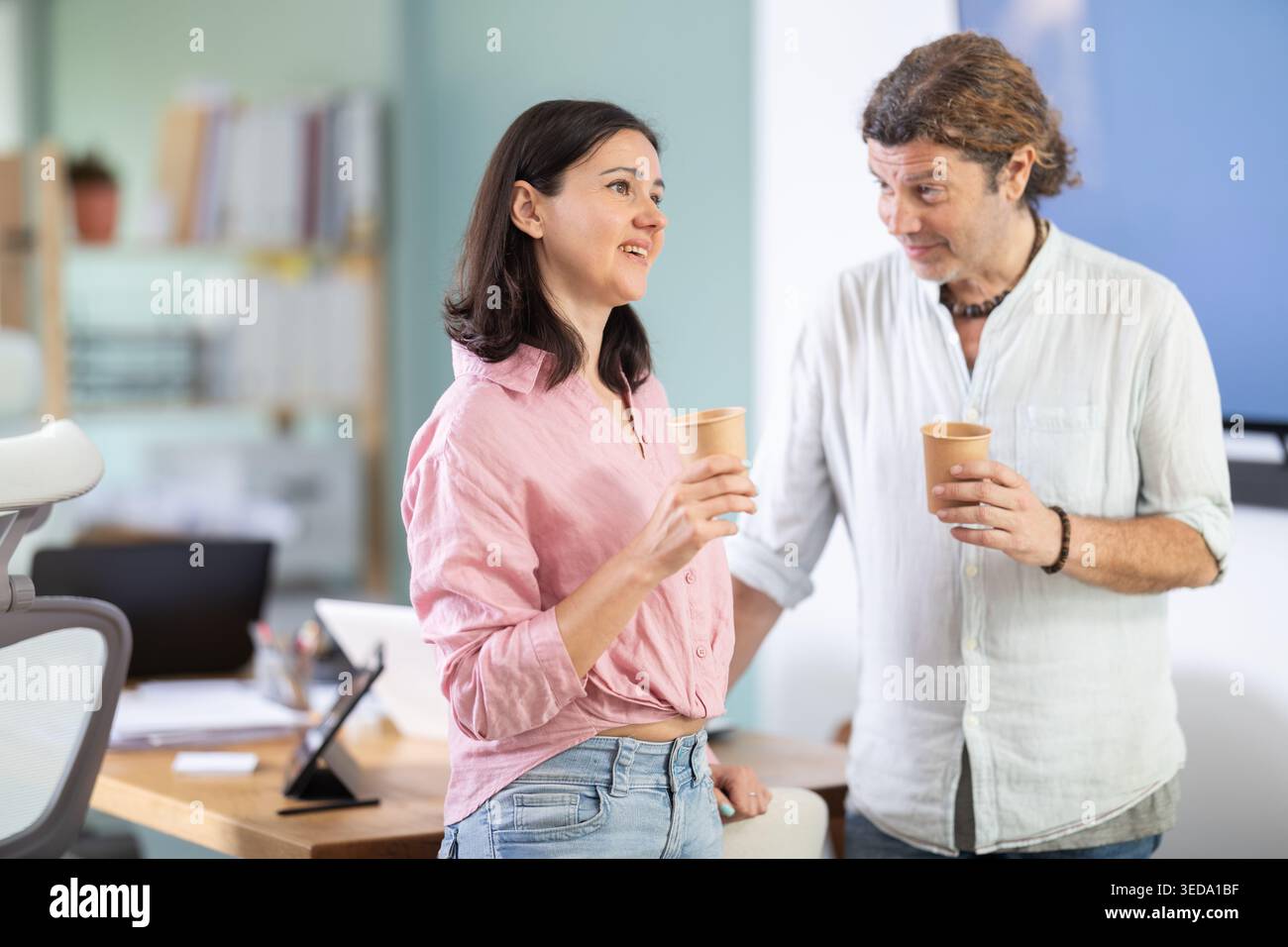 Middle-aged colleagues talking while holding coffee cup in office Stock Photo