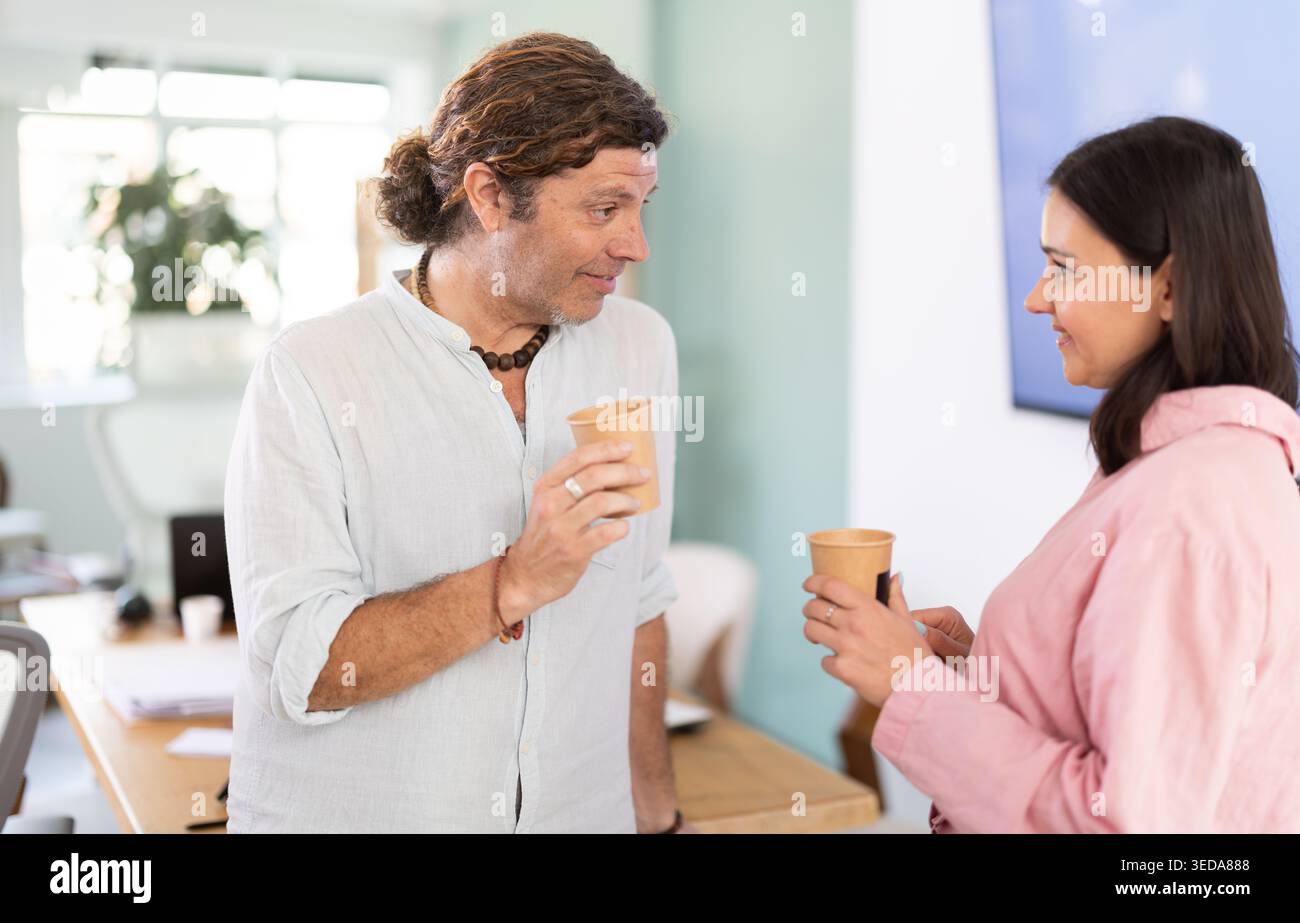 Middle-aged colleagues talking while holding coffee cup in office Stock Photo