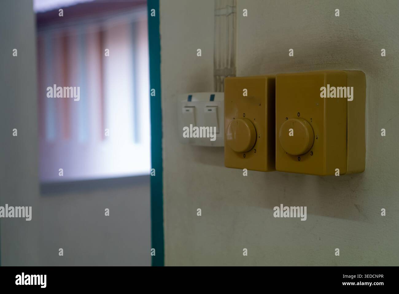 Close-up of a yellow light switch and dimmer on a wall in an interior setting, showcasing elements of modern residential decor and functionality in li Stock Photo