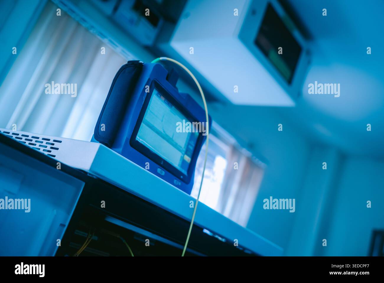 A close-up view of a medical monitor in blue light, displaying data and measurements. The modern workspace highlights diagnostic tools in a clinical s Stock Photo