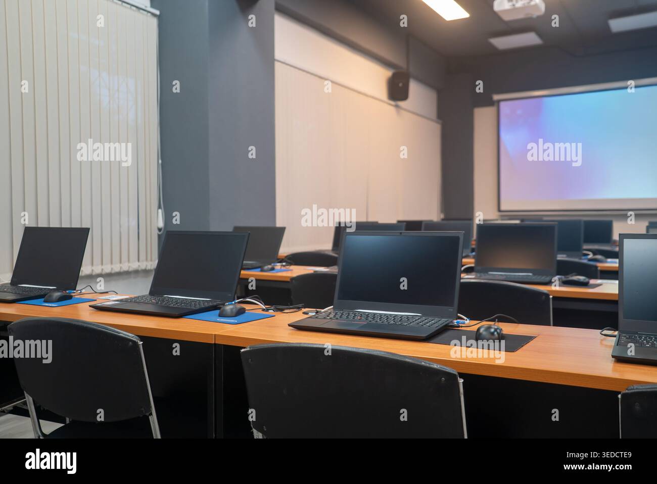 A modern classroom featuring rows of computer desks equipped with ...