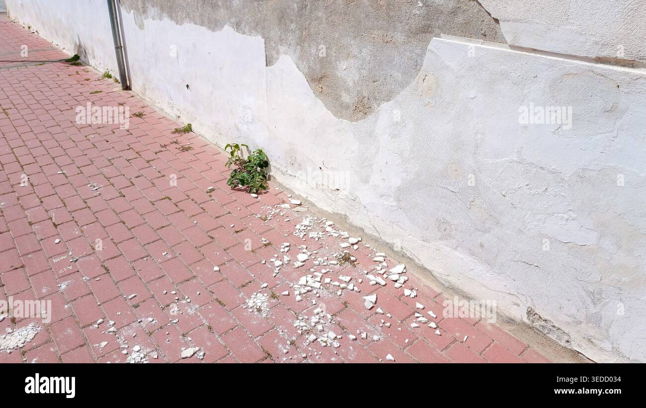 Peeling White Wall with Fallen Paint on Ground Stock Photo