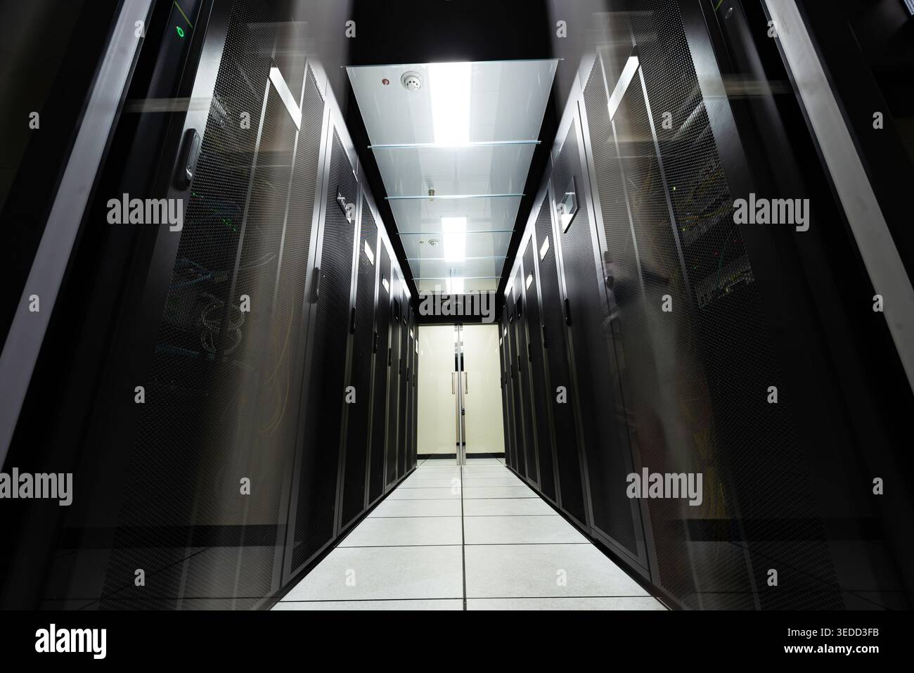 Explore a modern data center aisle filled with server racks. This environment showcases technology and infrastructure essential for data processing an Stock Photo