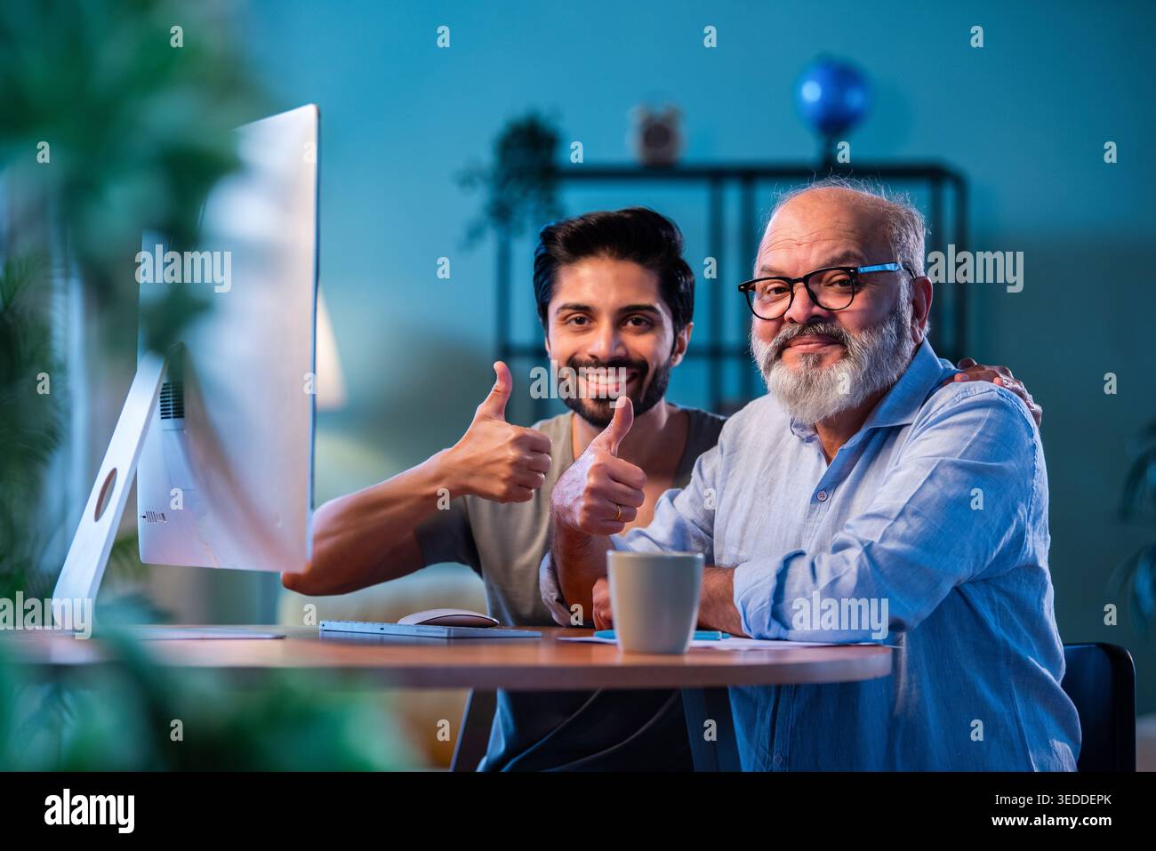 Indian young son teaching senior father how to use desktop computer at ...
