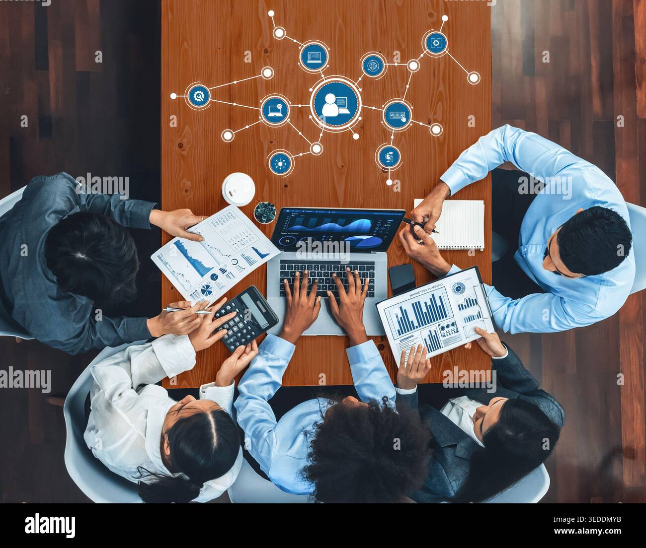 A diverse group of professionals collaborates in a modern office, analyzing data and charts around a laptop, showcasing teamwork and innovative ideas Stock Photo