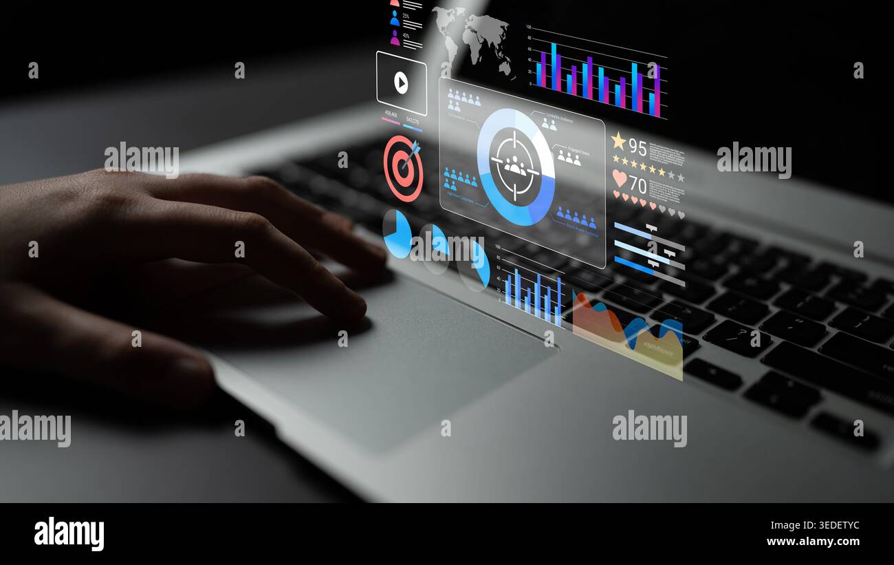 A hand interacts with a laptop screen displaying futuristic data visualizations. Graphs and interactive elements showcase technology and information Stock Photo