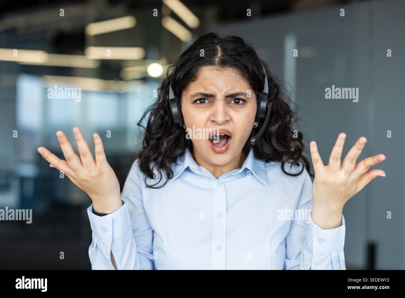 Busy customer support agent wearing headset, shouting and gripping hair ...
