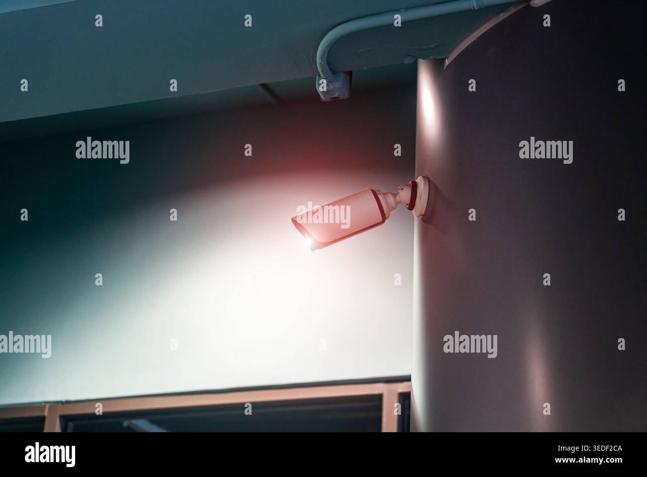 A modern surveillance camera mounted on a sleek wall, featuring a warning light, emphasizing security and monitoring in urban environments. Stock Photo
