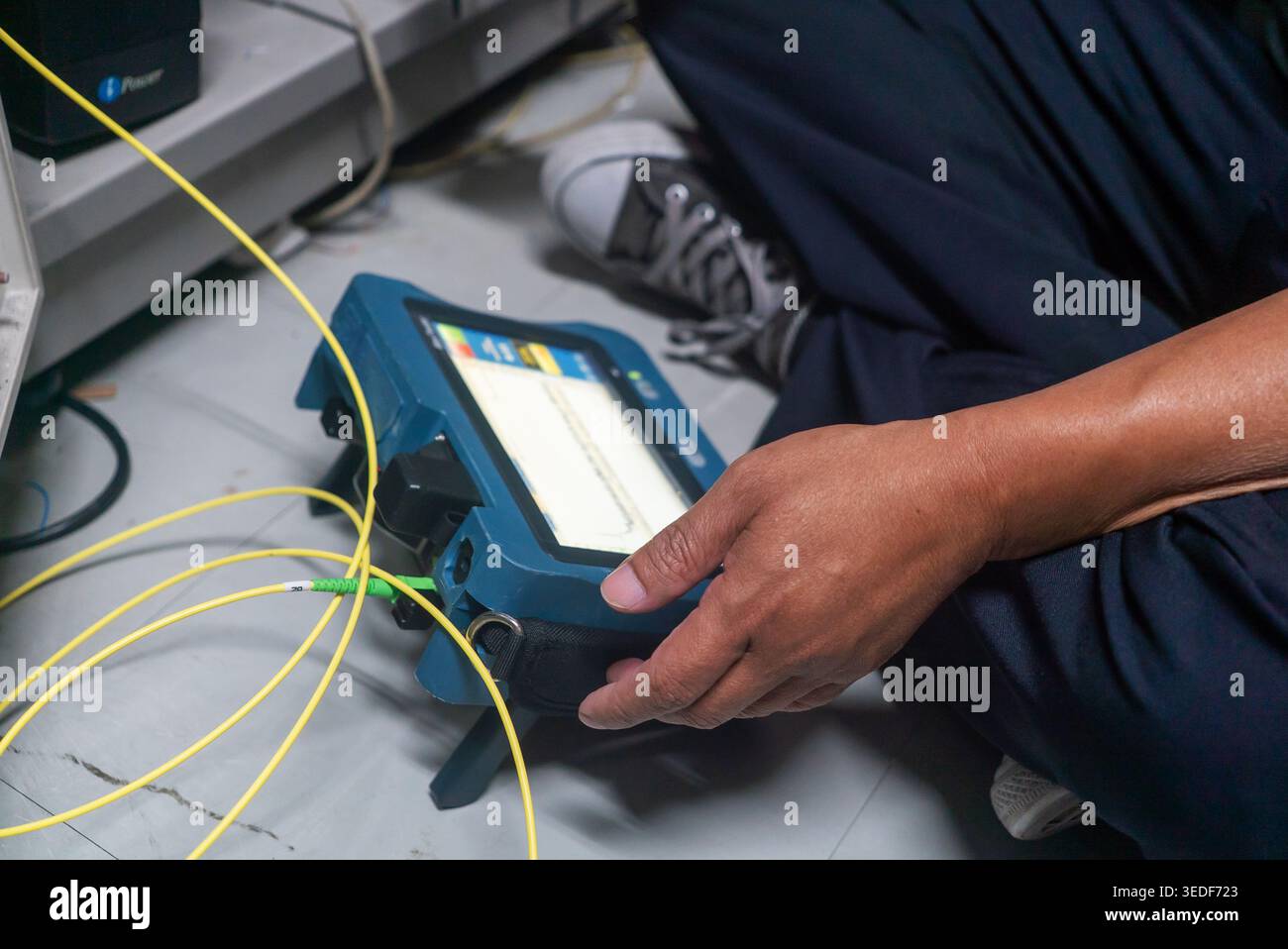 A technician works on network cables using a testing device, ensuring optimal connection and performance in a modern technological workspace. Stock Photo