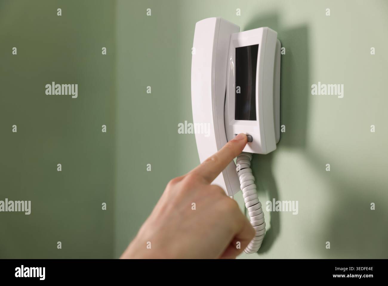 Man pressing button on intercom panel indoors, closeup Stock Photo
