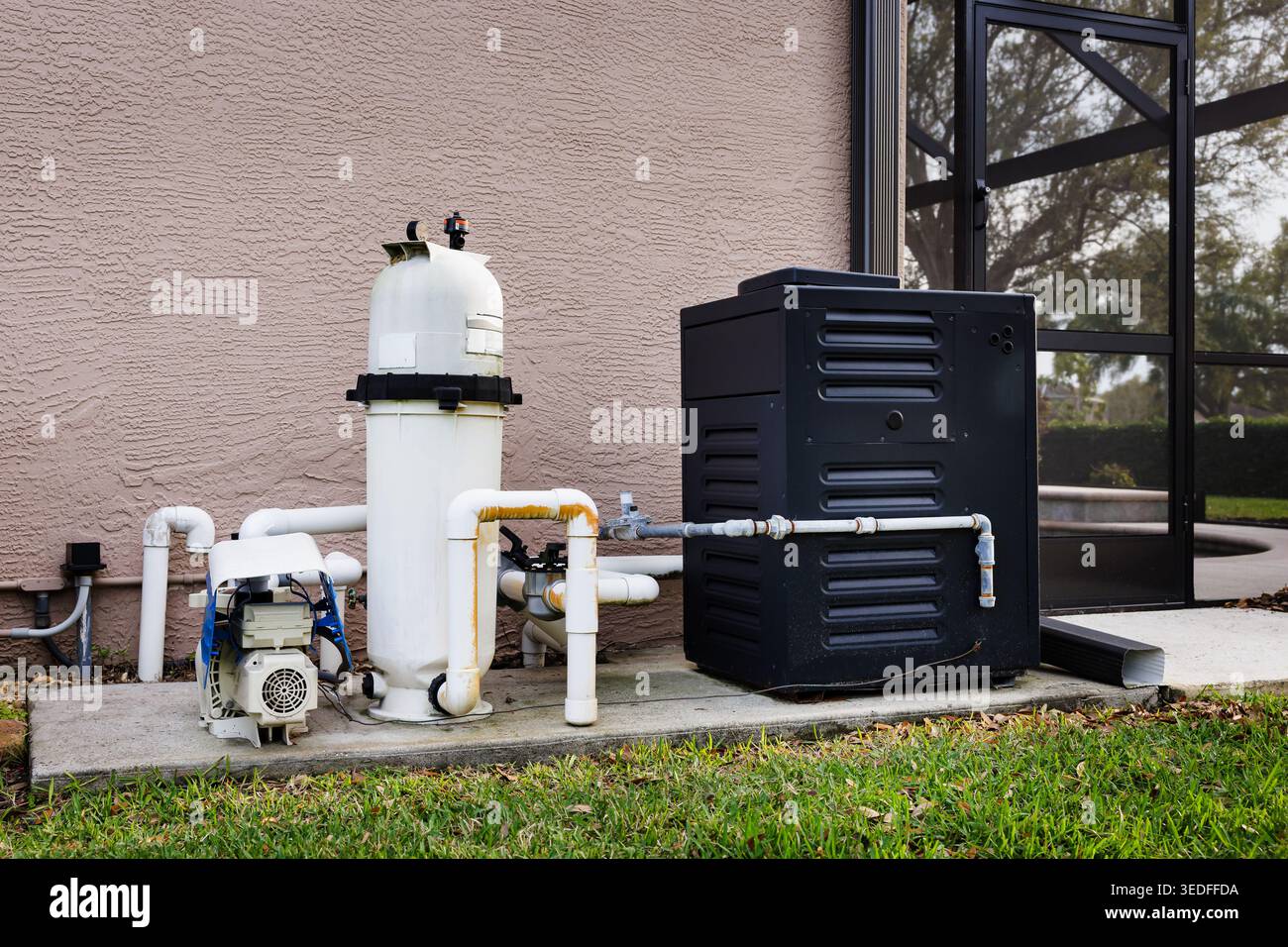 Modern natural gas swimming pool heater unit and pool water filtration equipment on concrete slab outside of house. Stock Photo