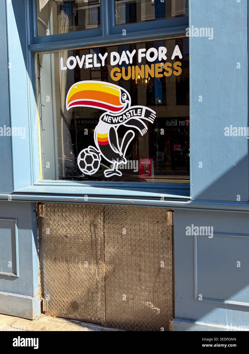 A vintage advertisement for Guinness with a toucan graphic and football theme displayed on a pub window in Newcastle - Smartphone Captured Stock Image