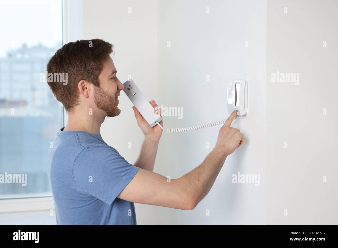 Man pressing button on intercom panel indoors Stock Photo
