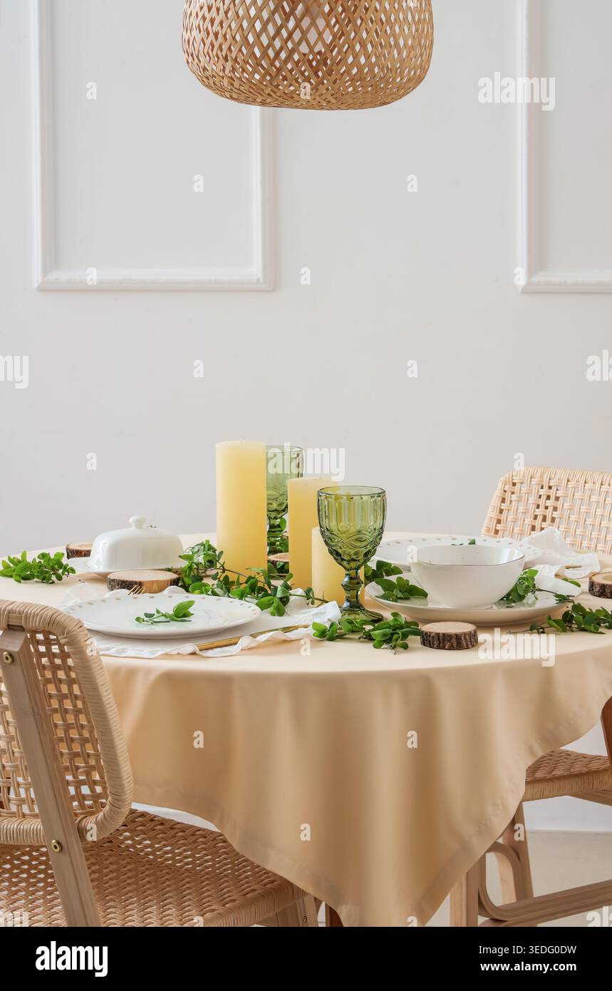 Beautiful table setting with plates, candles and green branches Stock Photo