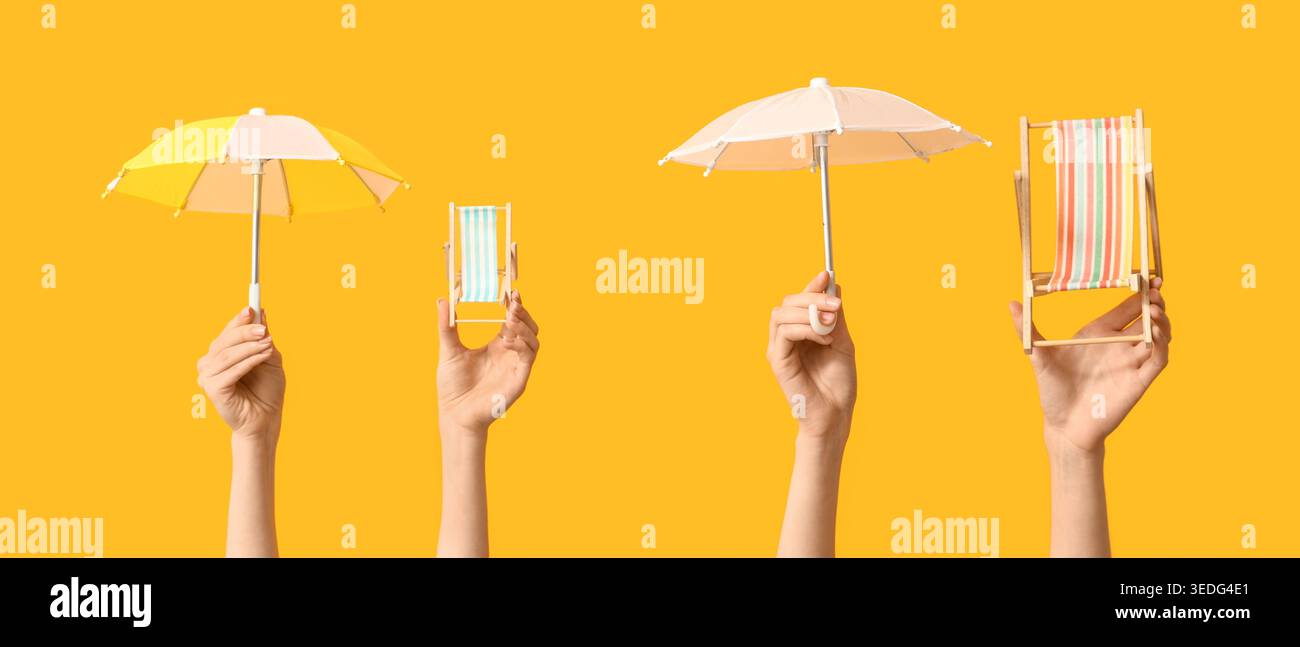 Hands holding mini deck chairs with umbrellas on yellow background Stock Photo
