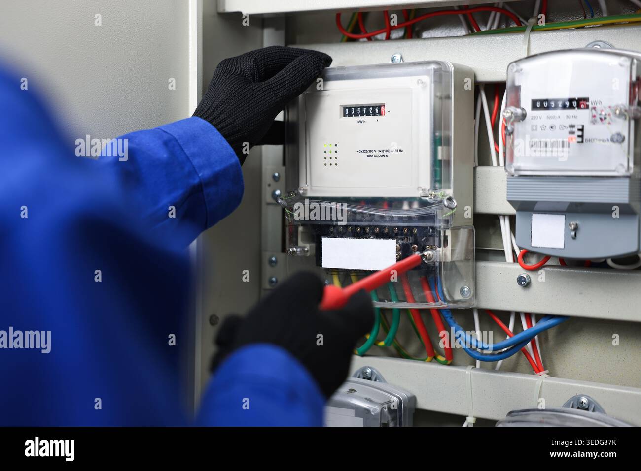 Electrician with screwdriver checking electrical meter indoors, closeup Stock Photo