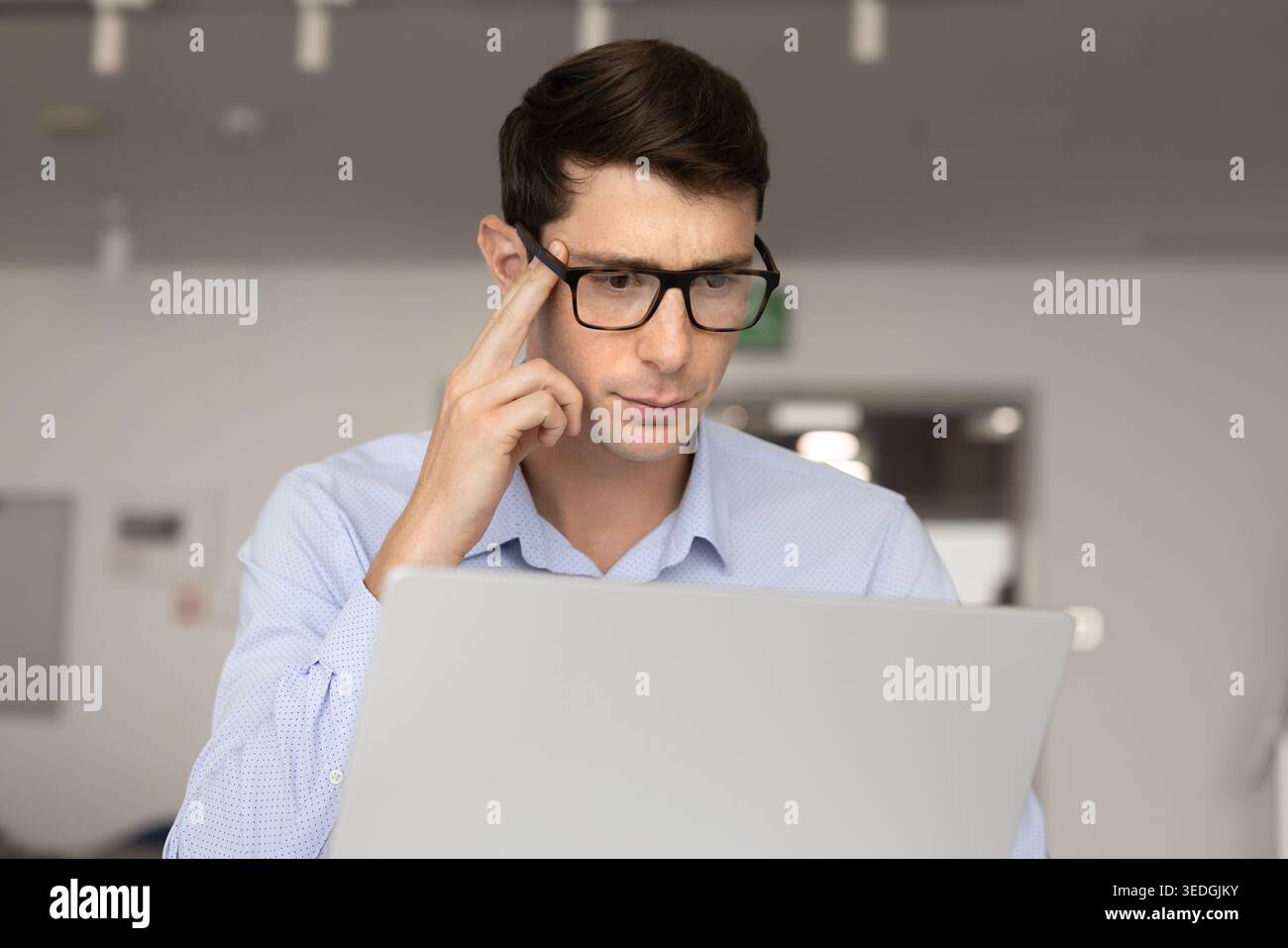 Focused young businessman thinking while working on laptop Stock Photo