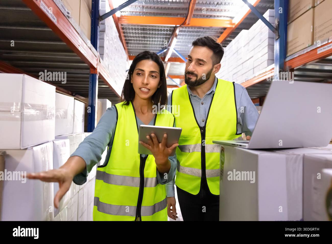 Two logistics workers discussing inventory in warehouse Stock Photo