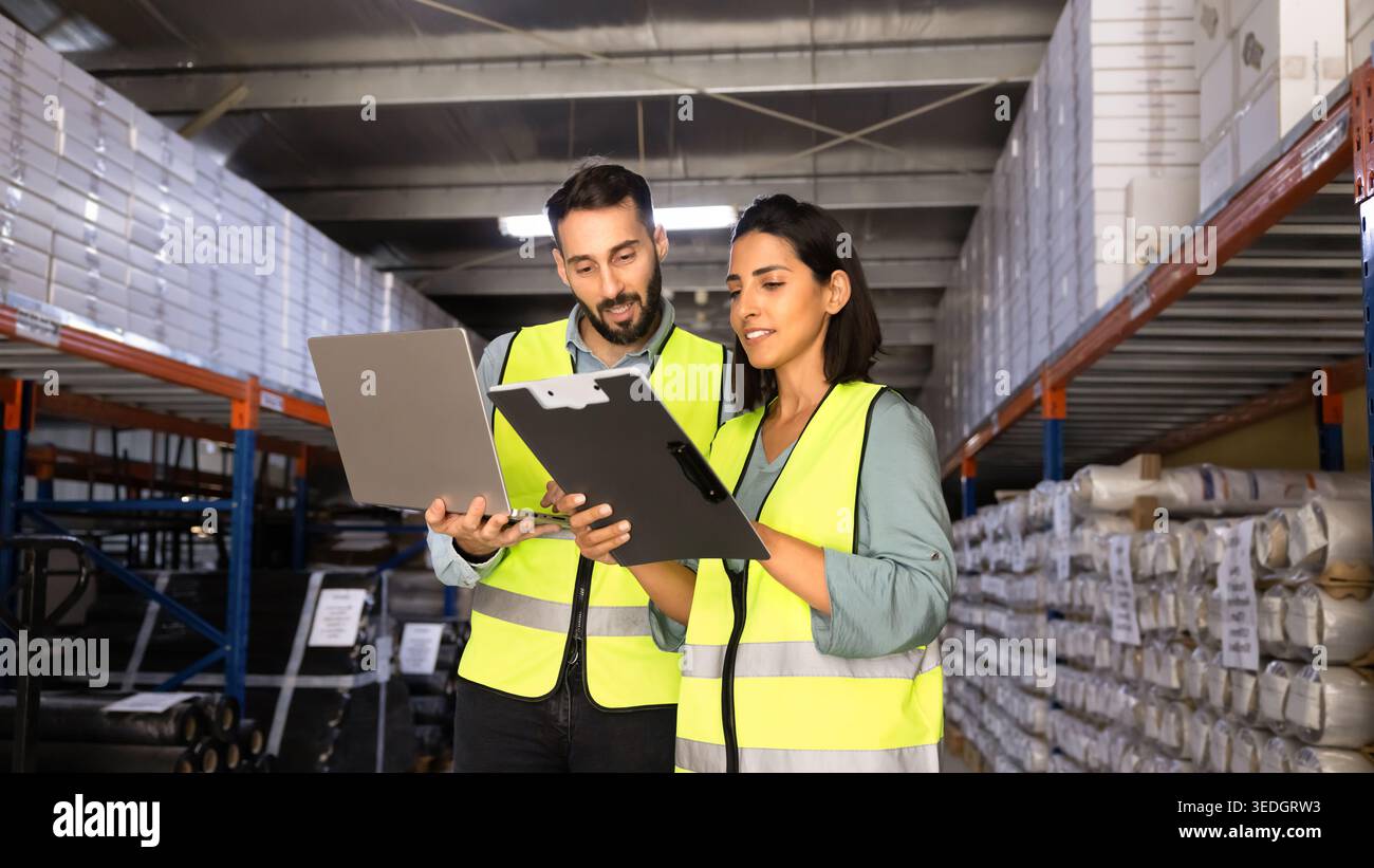 Latin warehouse workers working together using laptop Stock Photo