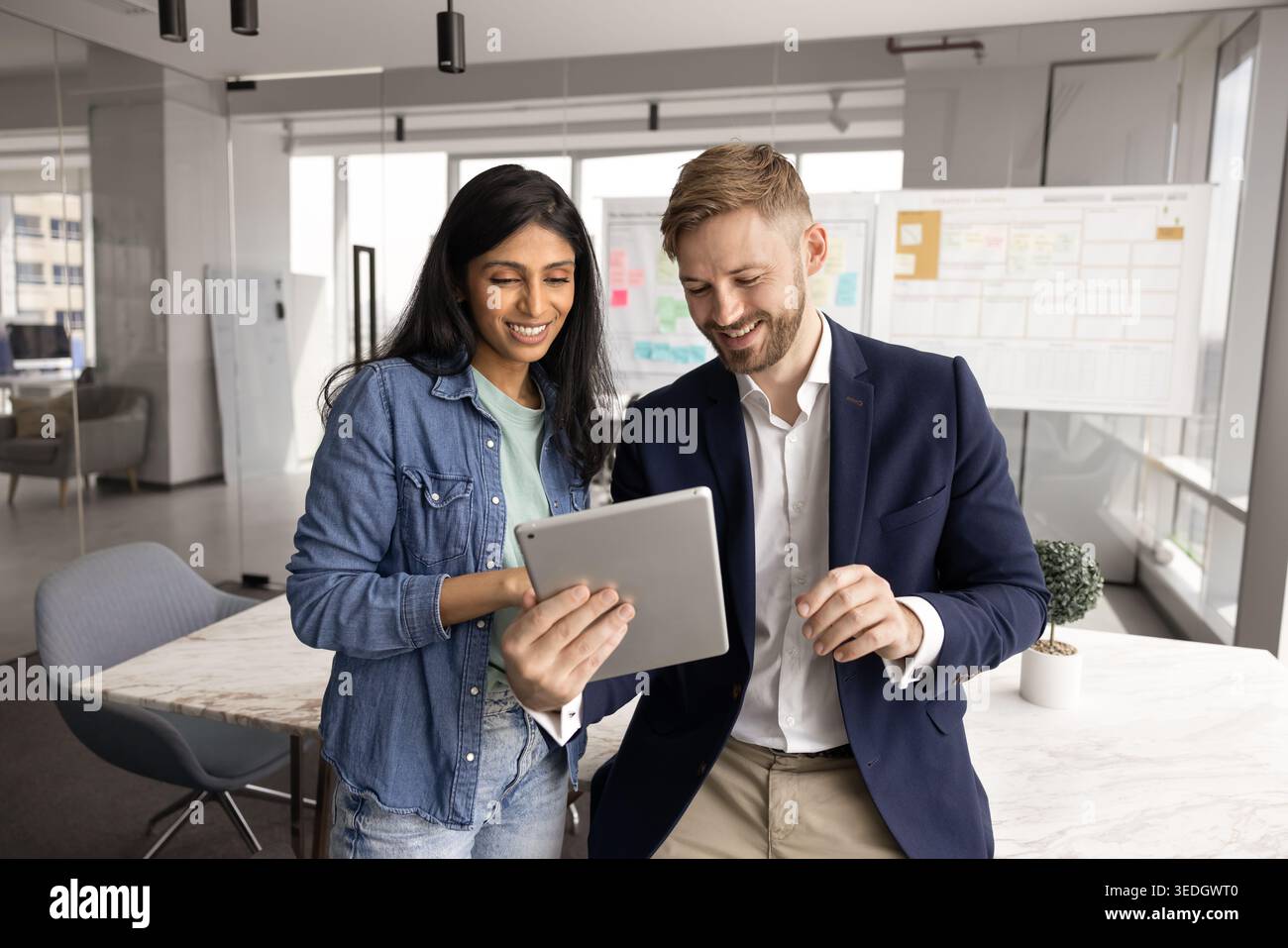 Two young 30s colleagues working on task using digital tablet Stock Photo