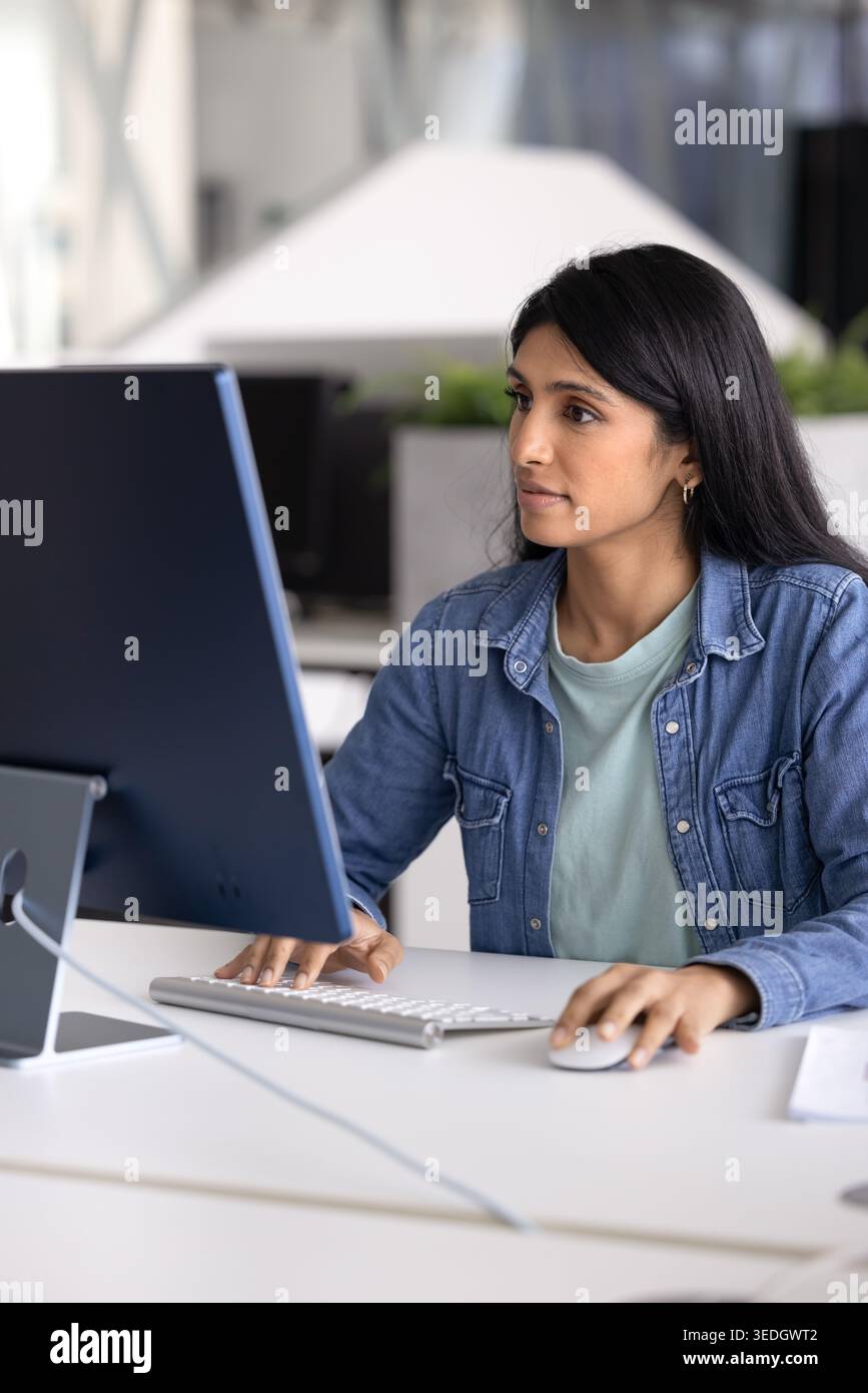 Young Indian woman analyzing reports, working on presentation using PC Stock Photo
