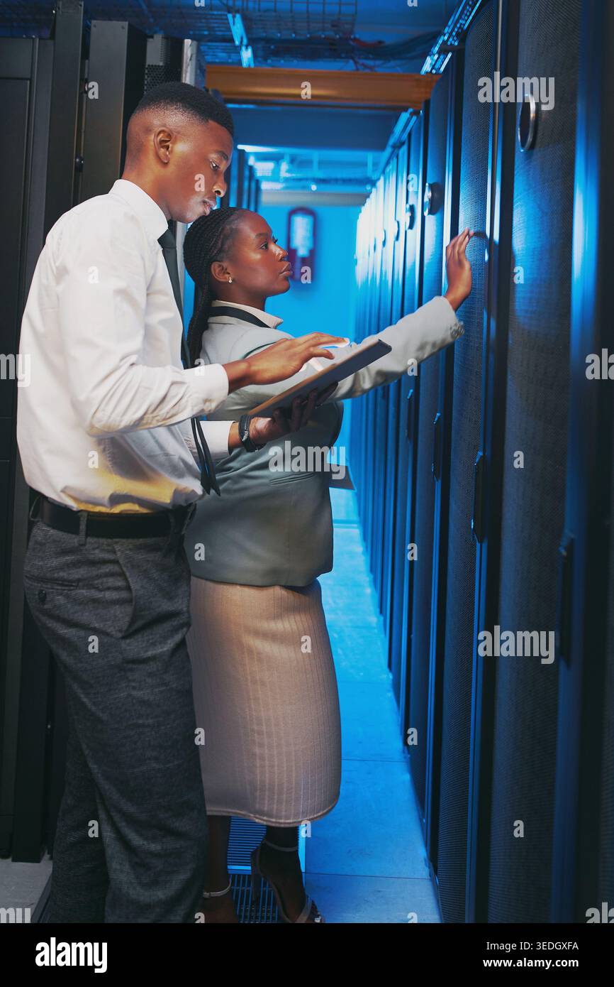 Black people, mainframe and programmer with tablet in server room for research, coding or cybersecurity. Team, review and digital for software update Stock Photo