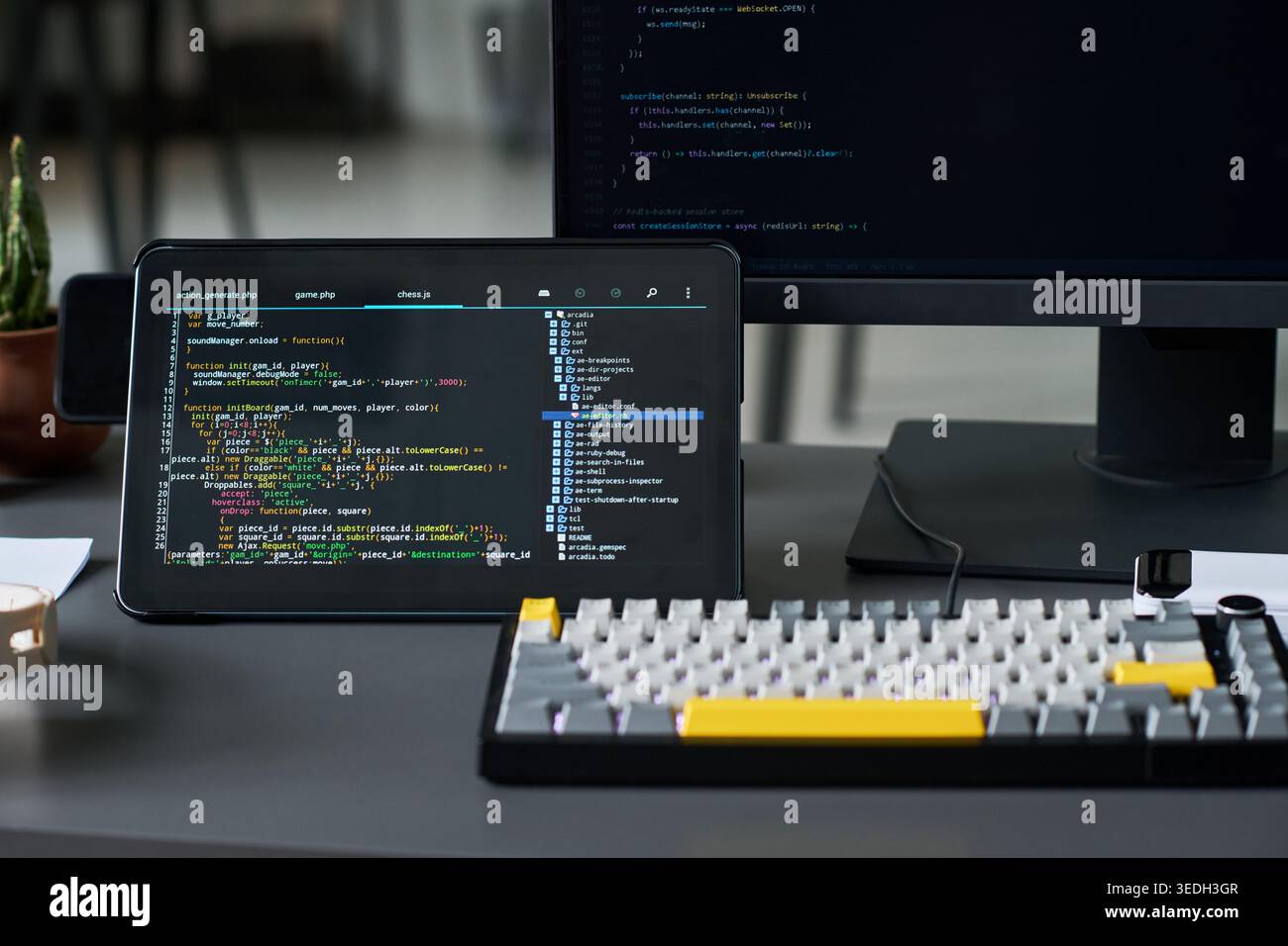 Close up of coding workspace displaying software development on tablet and monitor, showing programming and debugging. Useful for app development, IT training, tech marketing Stock Photo