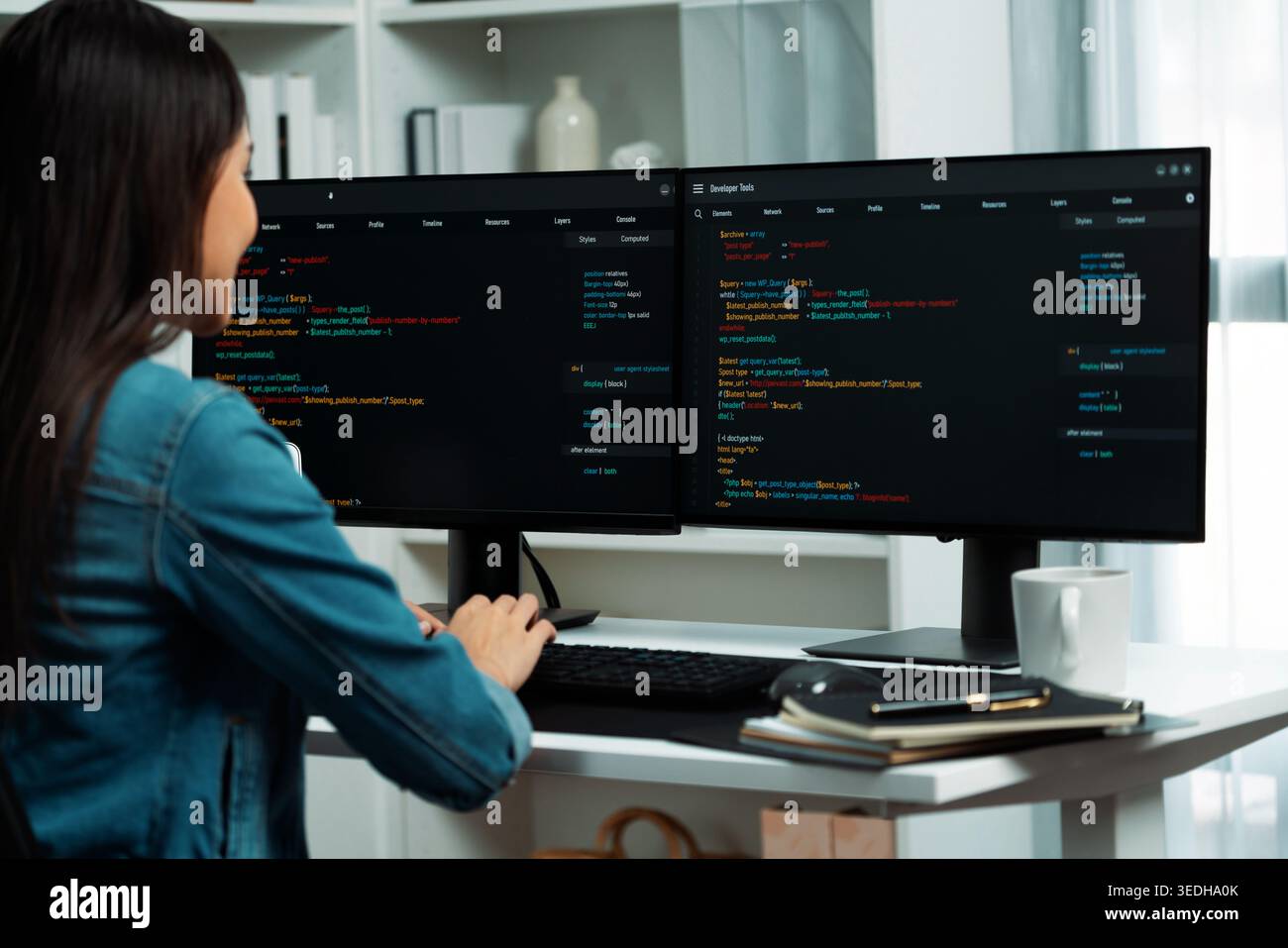 Young Asian in IT developer creating with typing online information on pc with coding program data of website application, wearing jeans shirt Stock Photo