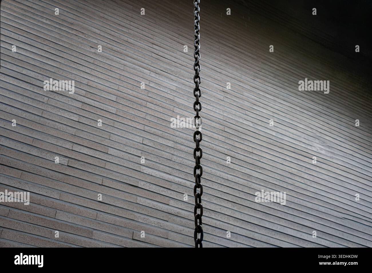 Hanging Chain against a Minimal Brick Wall Background Stock Photo