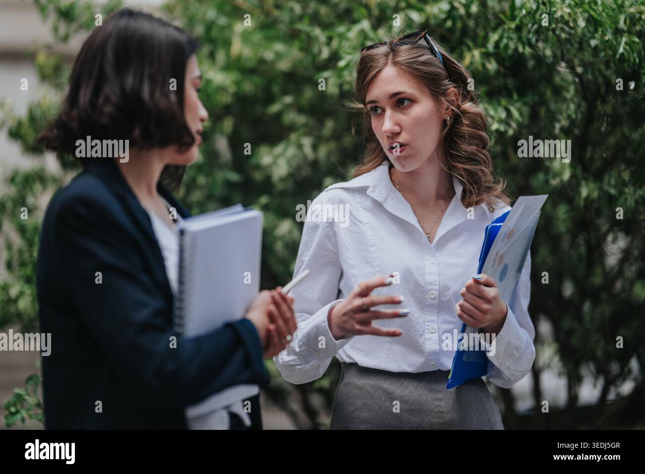 Two business colleagues discussing documents outdoors during a professional conversation Stock Photo