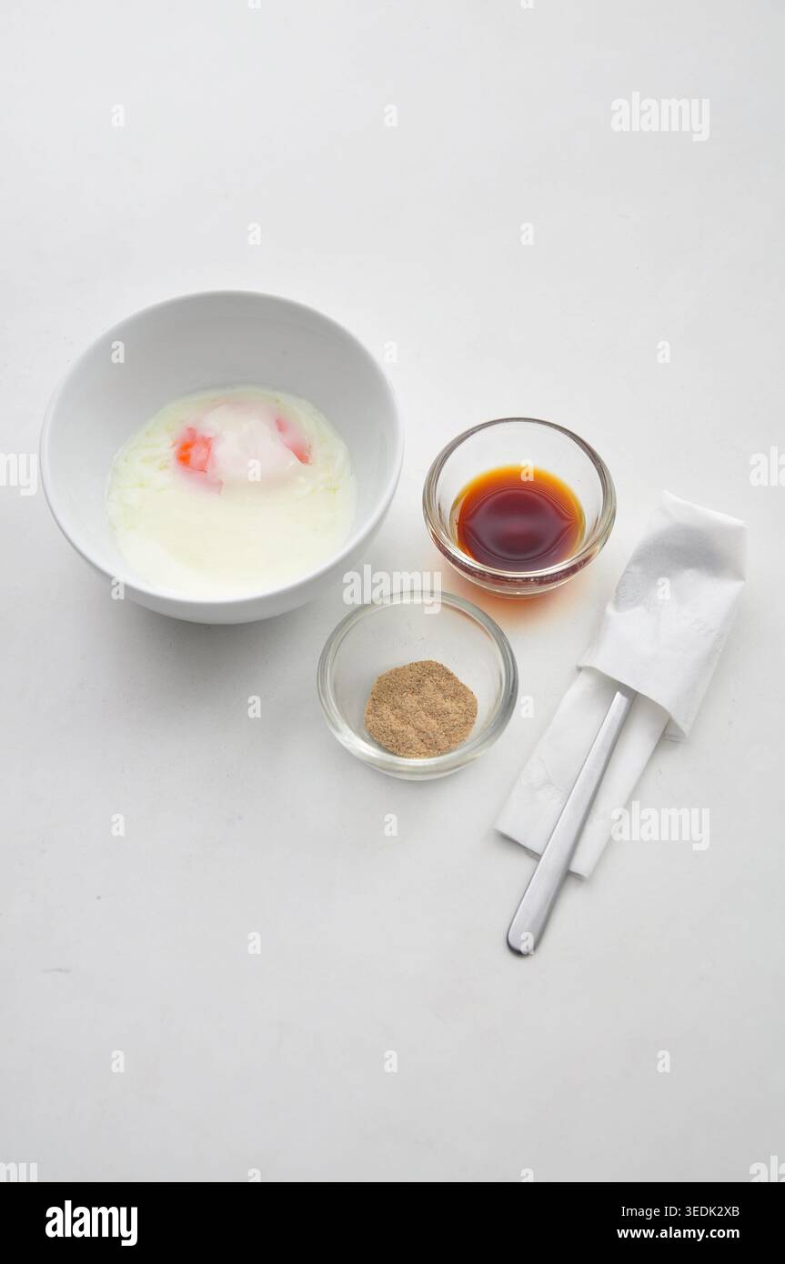 soft boiled egg or half boiled egg served with soy sauce and white pepper served in a white bowl on white table, kopitiam style Stock Photo