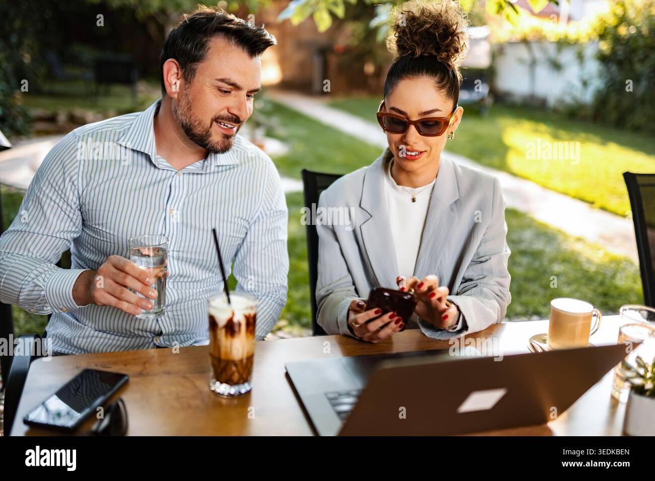 Business colleagues collaborating outdoors using mobile technology Stock Photo