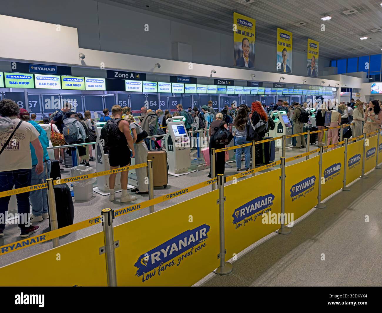 Passengers queue at Ryanair self-service bag-drop desks in Terminal 3 at Manchester Airport before low-cost flights across Europe Stock Photo