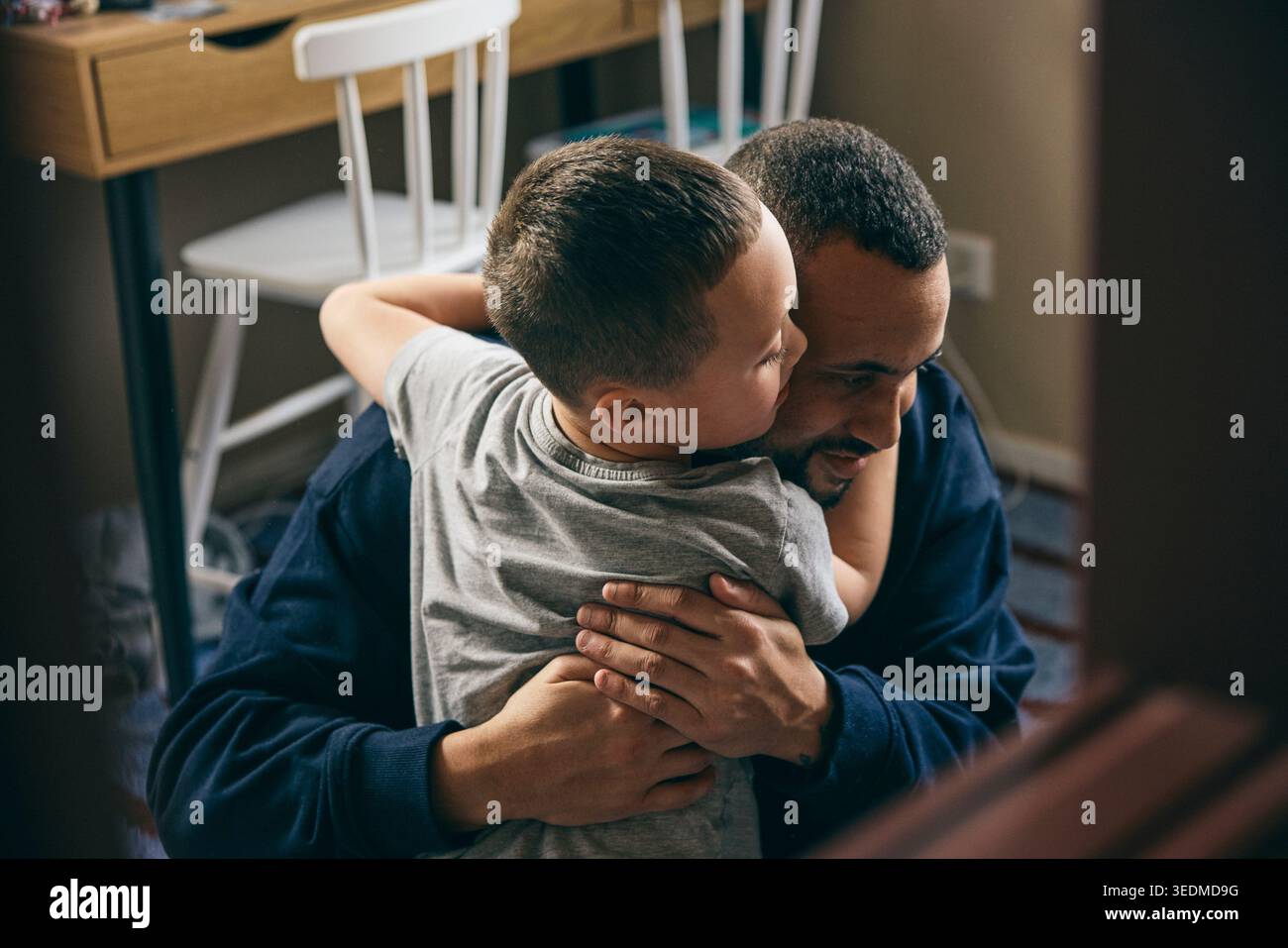 Affectionate boy embracing father at home Stock Photo