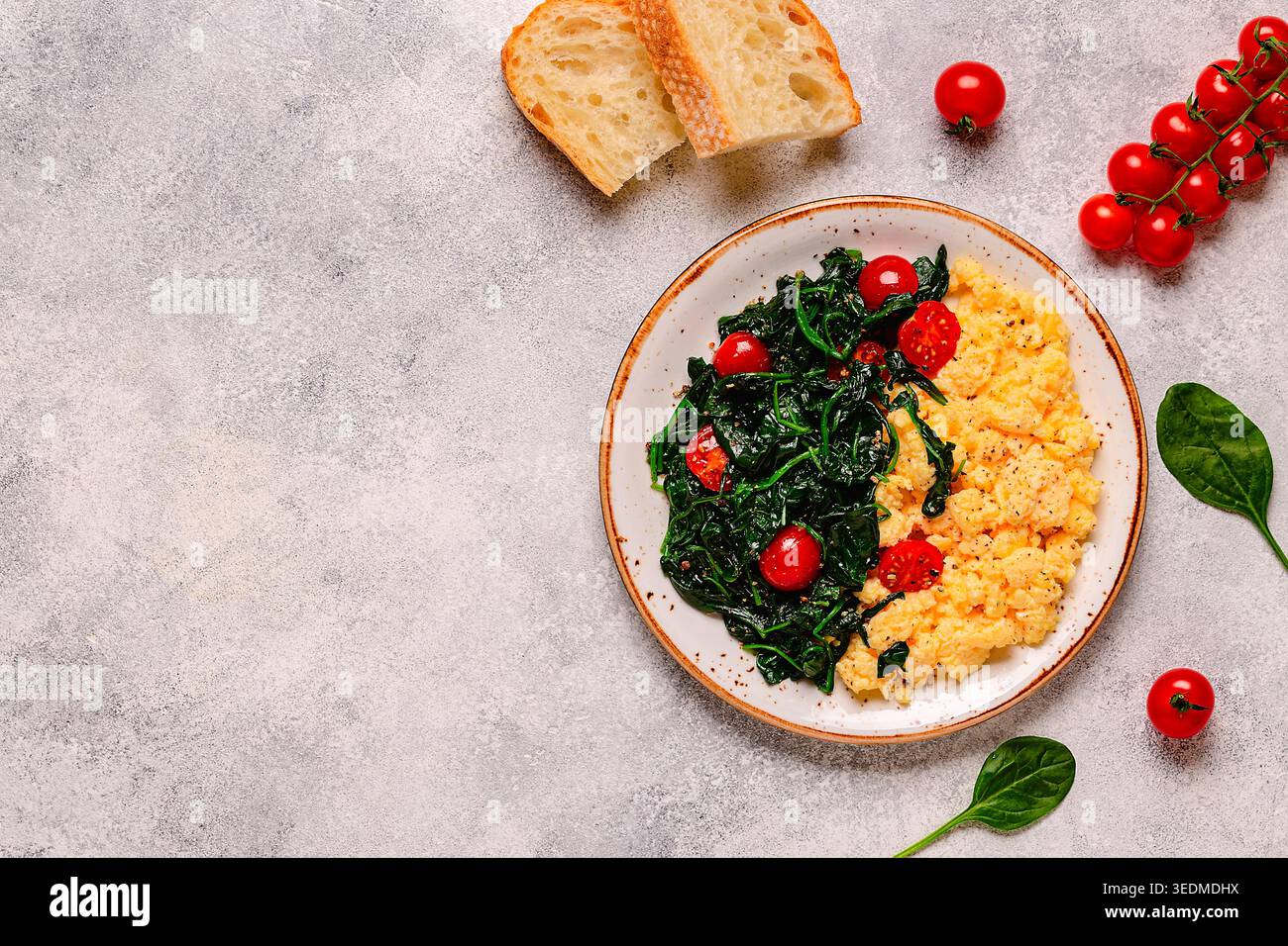 Cooked omelette and spinach with tomatoes on a light background, top view. Stock Photo