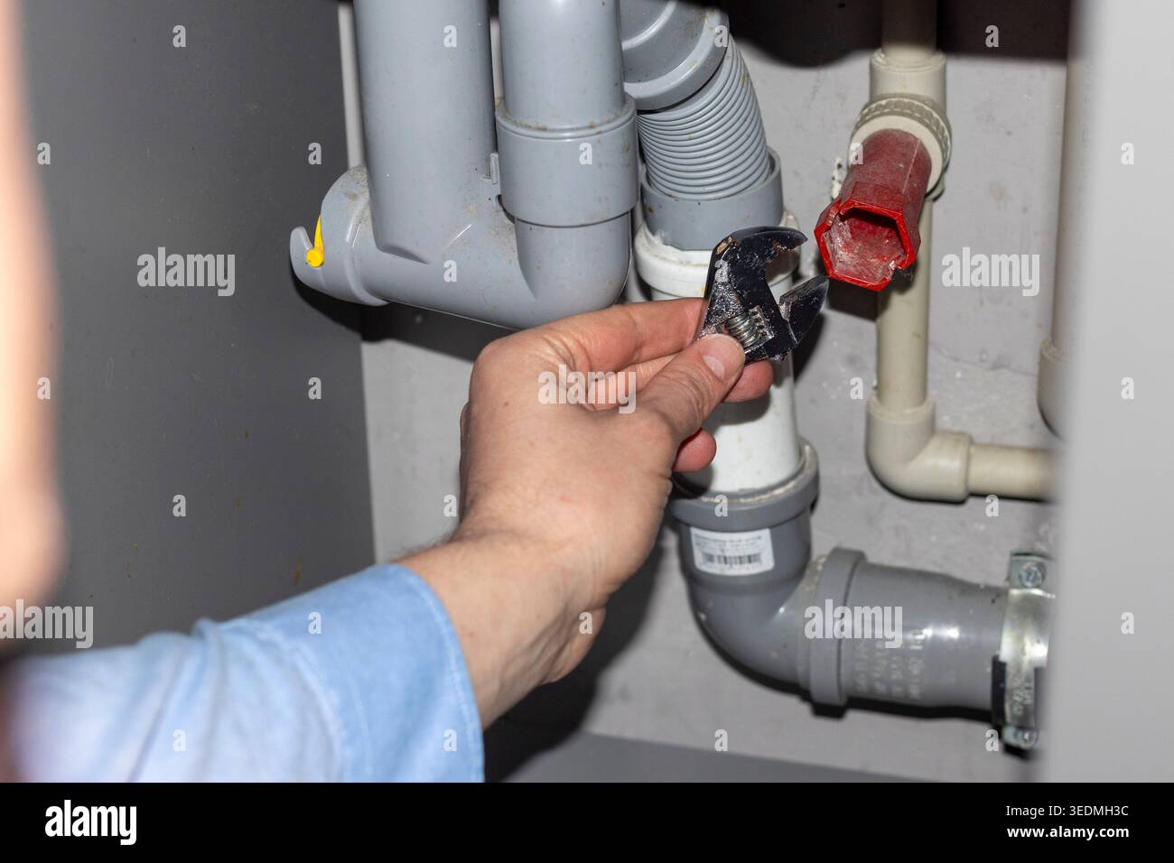 Plumber working on the plumbing drain pipes under a sink Stock Photo