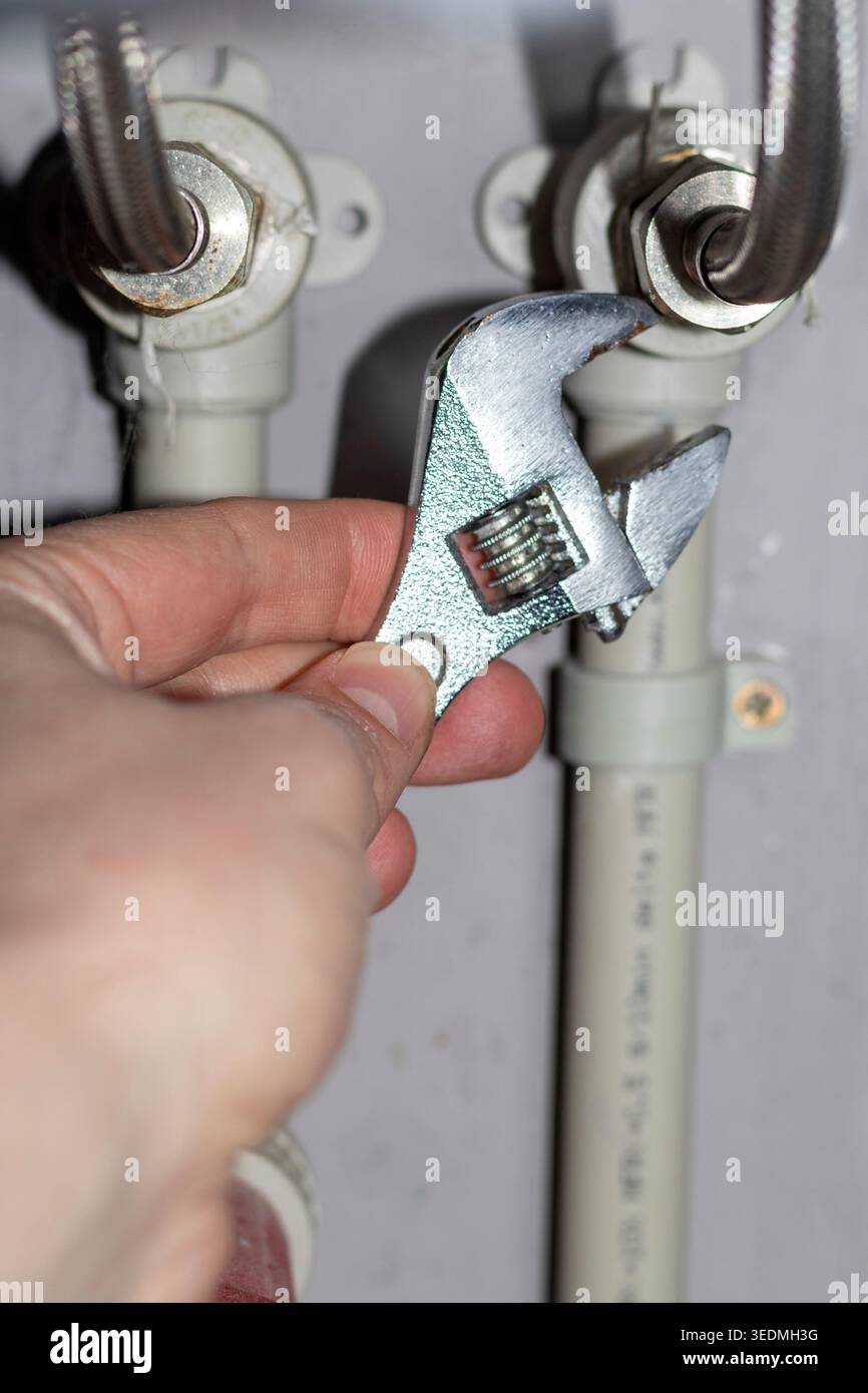 Plumber working on the plumbing drain pipes under a sink Stock Photo