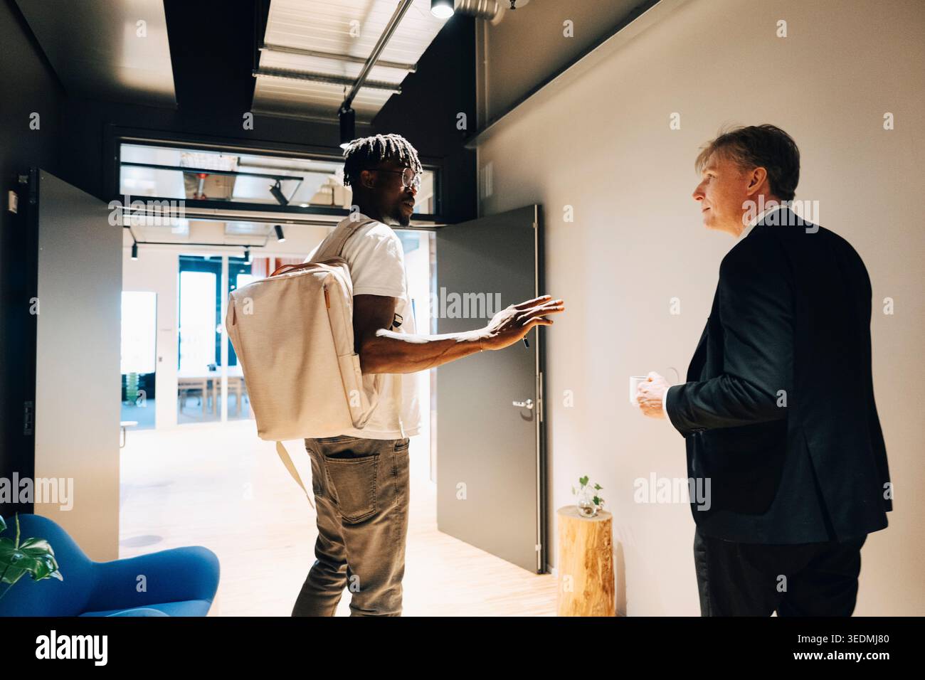 Male employee talking with investor while walking in office corridor Stock Photo