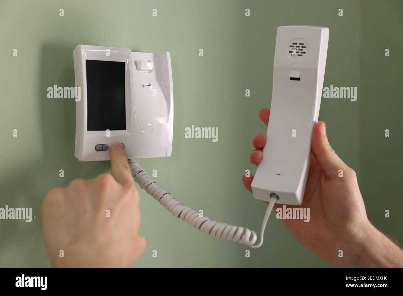 Man with handset pressing button on intercom panel indoors, closeup Stock Photo