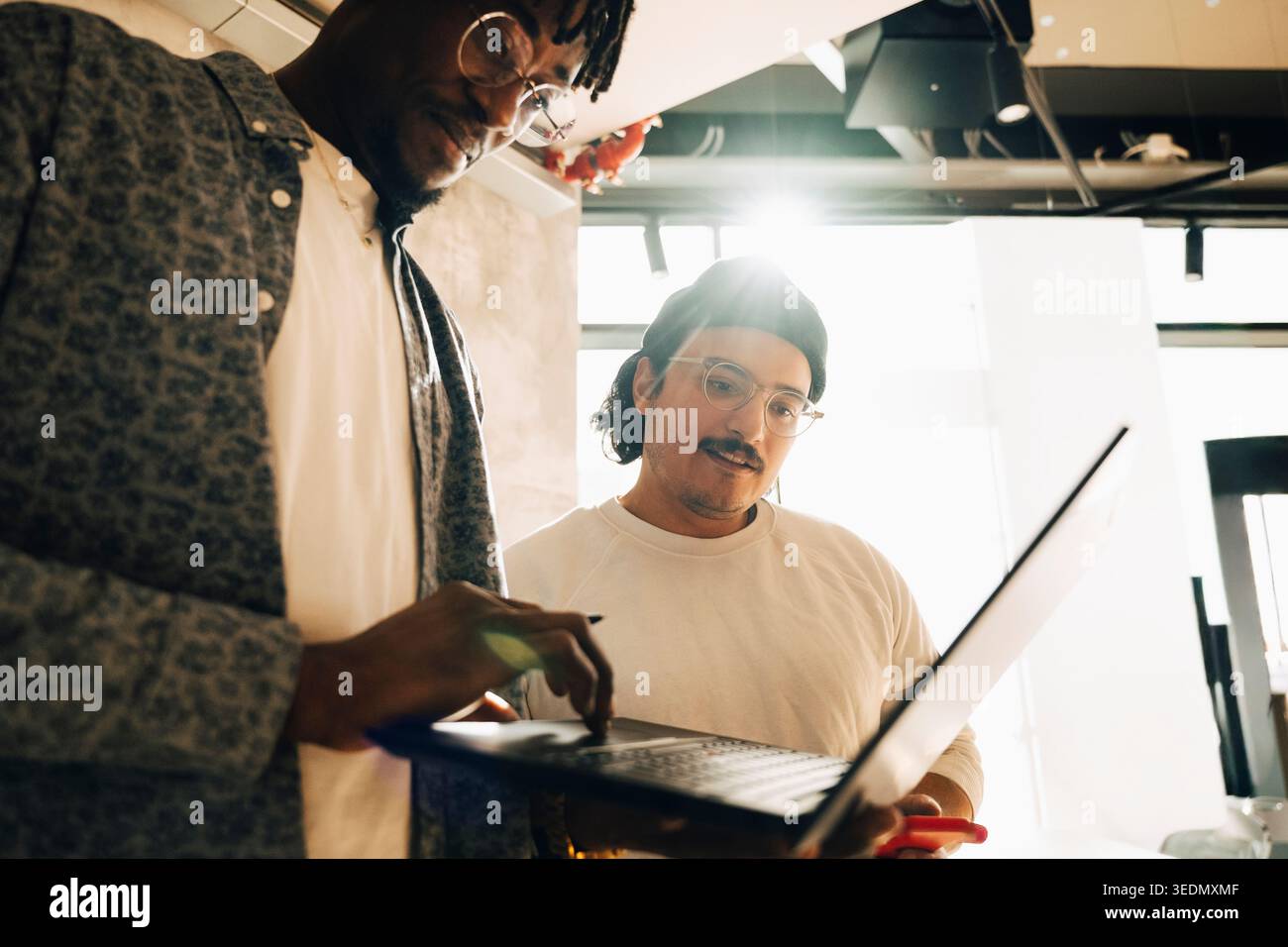 Focused computer programmers working on laptop at startup workspace Stock Photo