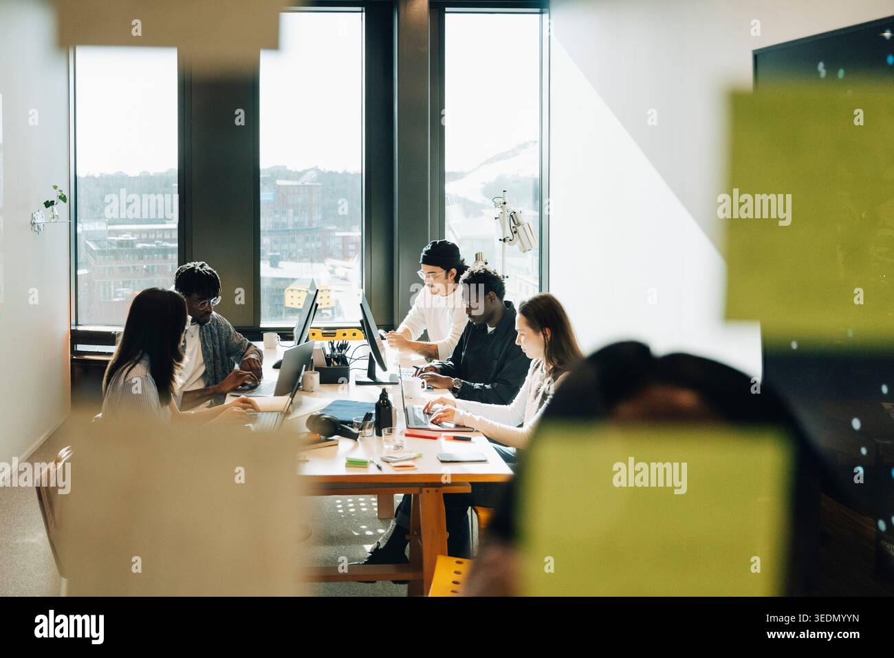 Group of diverse computer programmers working together while sitting around table at creative workspace Stock Photo