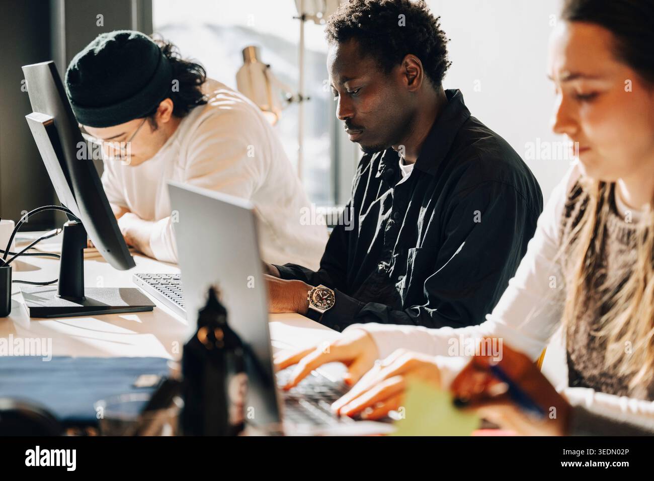 Group of focused programmers working on computers at desk in office Stock Photo