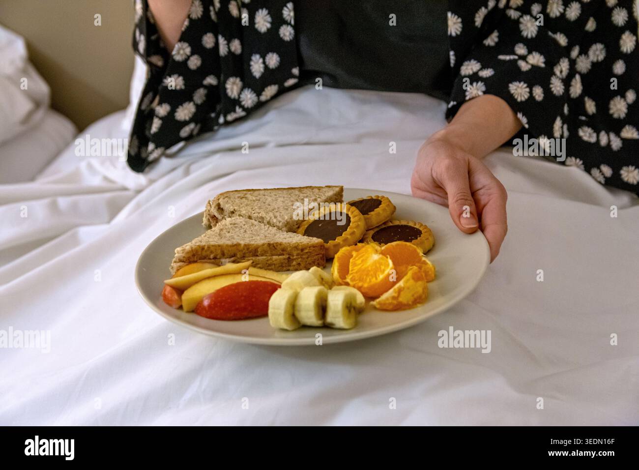 Person holding breakfast in bed for morning routine Stock Photo