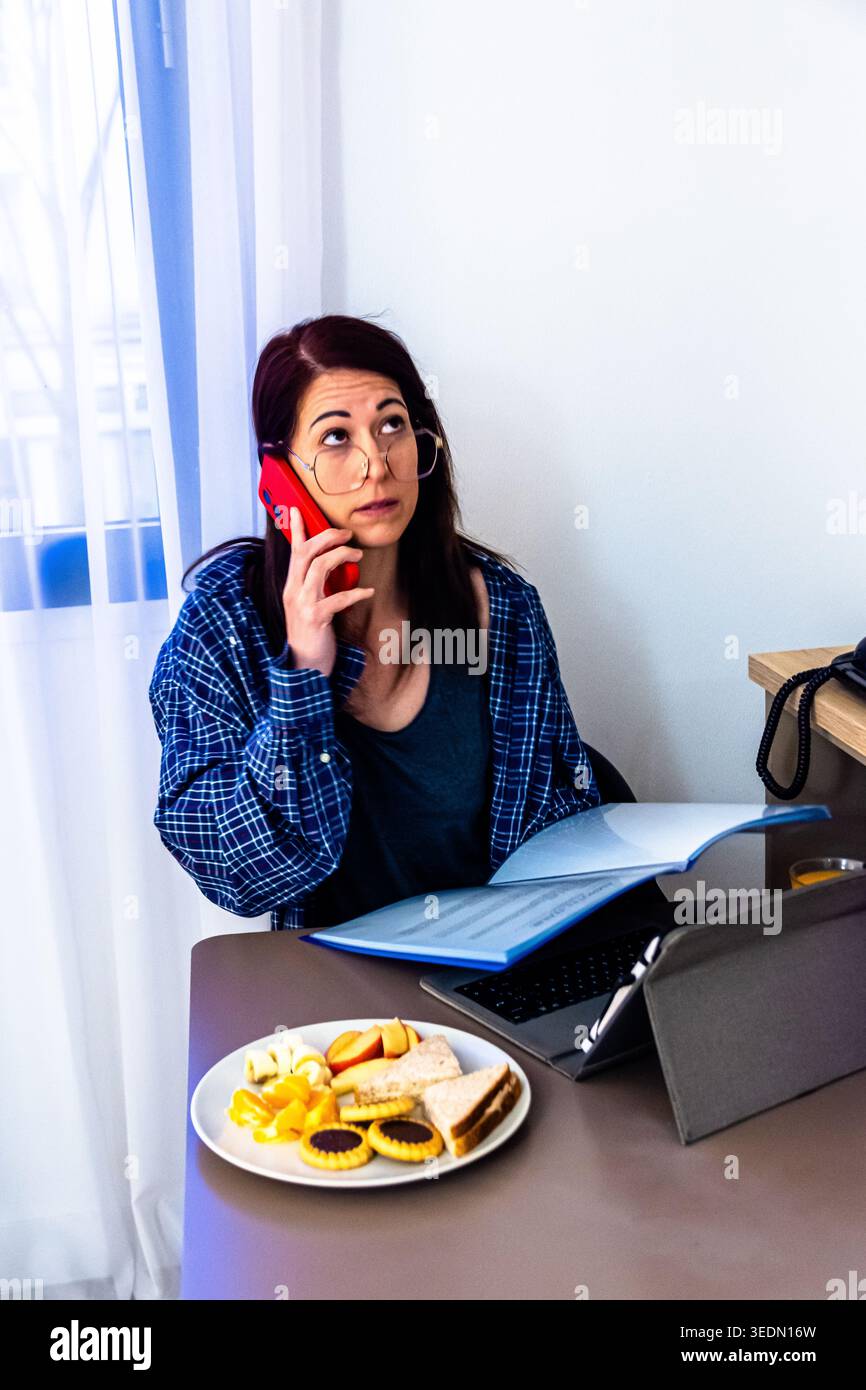 Woman multitasking working remotely having breakfast Stock Photo