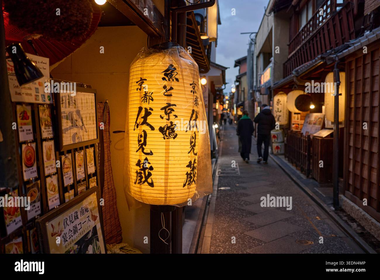 People walking at dusk in Pontocho, a narrow, atmospheric alley lined with old picturesque buildings in Kyoto, Japan. Stock Photo